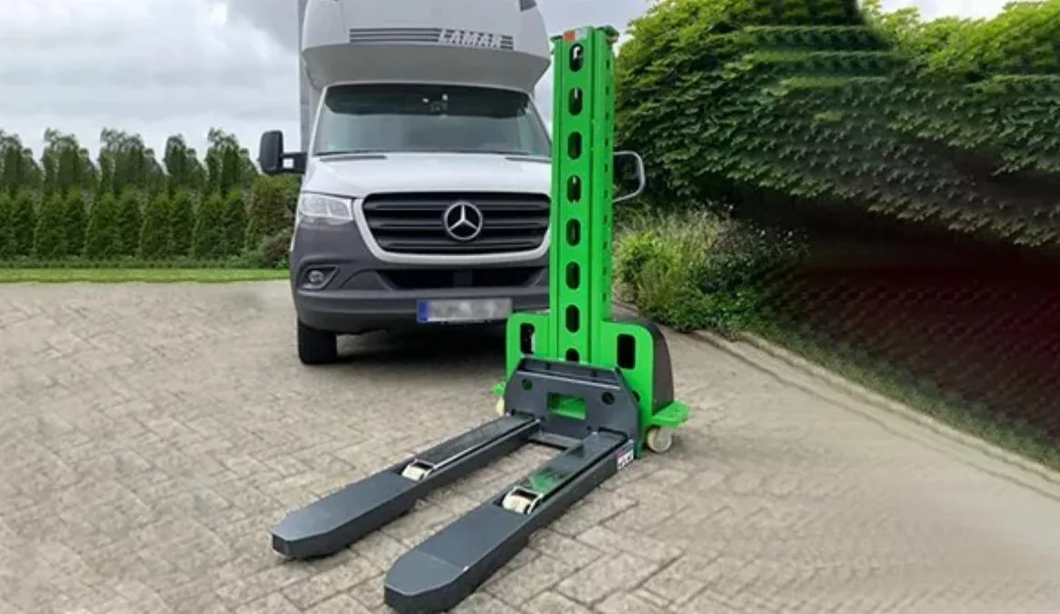 Transpaleta eléctrica autocargable con horquillas al frente, junto a un utilitario